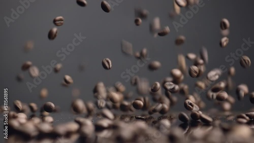 Brown coffee grains falling on surface bouncing closeup. Dawnfall roasted seeds. photo