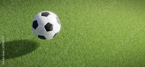Classic football or soccer ball floating against grass pitch backdrop. © HTGanzo