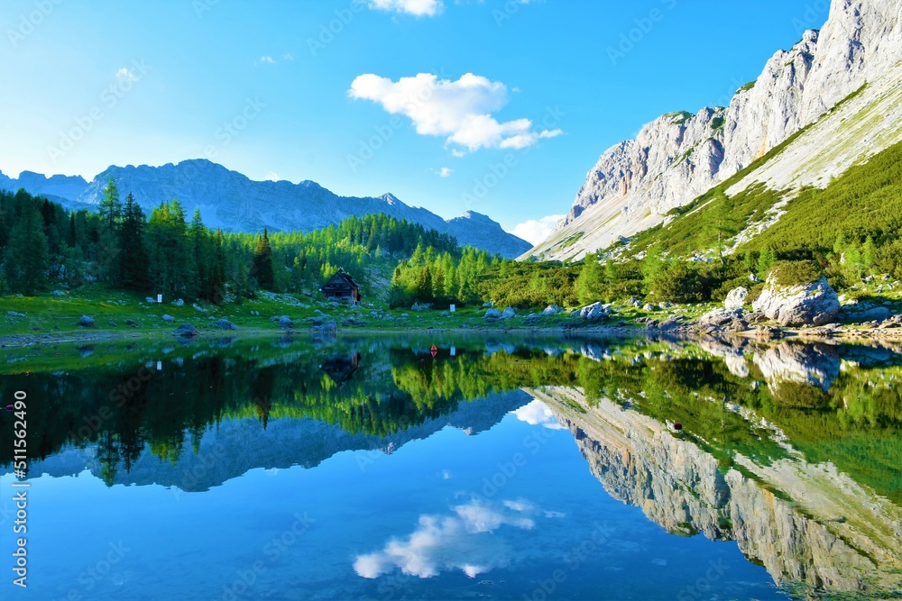 Scenic view of Double lake or Dvojno jezero at Triglav lakes valley with the reflection of the surrounding mountains in the lake and a larch forest on the other