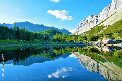Scenic view of Double lake or Dvojno jezero at Triglav lakes valley with the reflection of the surrounding mountains in the lake and a larch forest on the other