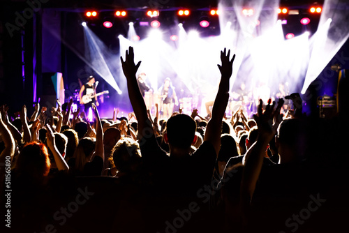 Concert crowd attending a concert, people silhouettes with backlit by stage lights
