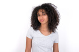 Displeased Young beautiful girl with afro hairstyle wearing grey t-shirt over white wall frowns face feels unhappy has some problems. Negative emotions and feelings concept