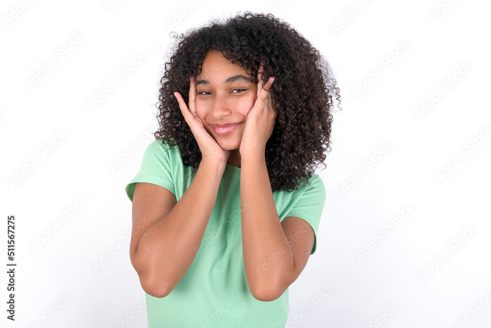 Young beautiful girl with afro hairstyle wearing green t-shirt over white background Pleasant looking cheerful, Happy reaction