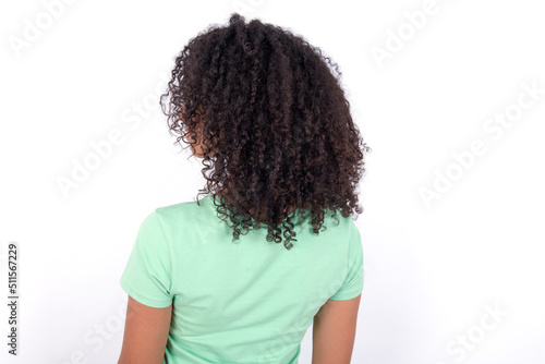 The back side view of a Young beautiful girl with afro hairstyle wearing green t-shirt over white background . Studio Shoot.
