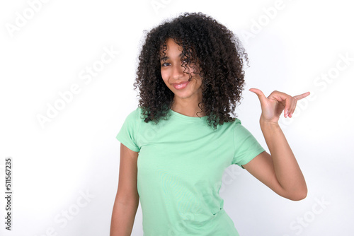 Young beautiful girl with afro hairstyle wearing green t-shirt over white background showing up number six Liu with fingers gesture in sign Chinese language
