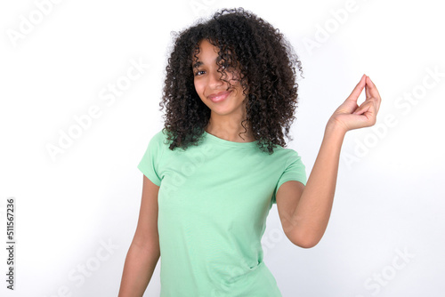 Young beautiful girl with afro hairstyle wearing green t-shirt over white background pointing up with hand showing up seven fingers gesture in Chinese sign language QÄ«. © Roquillo