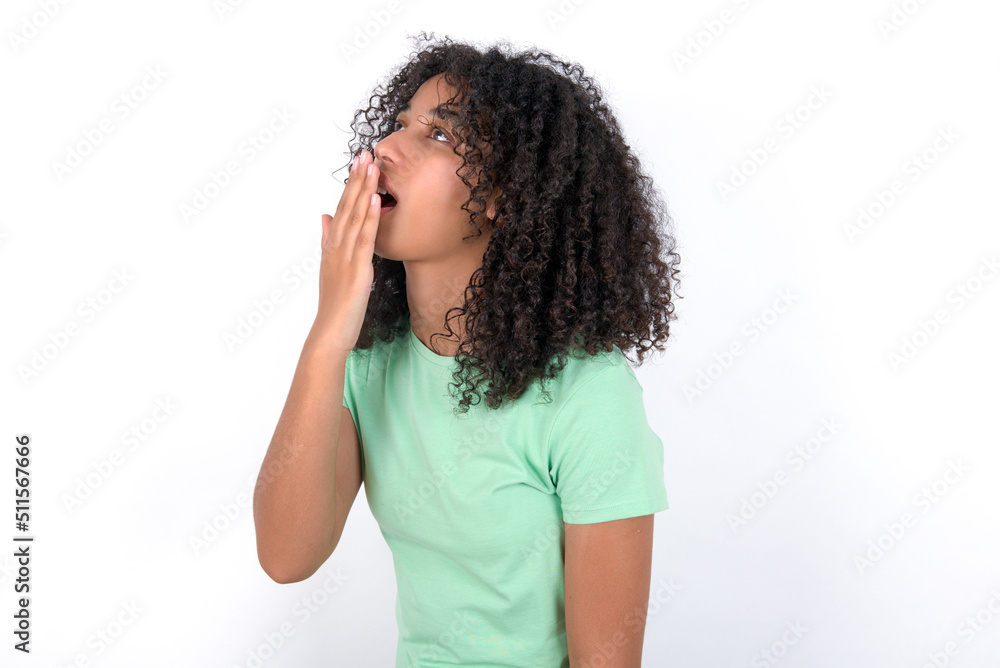 Young beautiful girl with afro hairstyle wearing green t-shirt over white background being tired and yawning after spending all day at work. Young beautiful girl with afro hairstyle wearing green t-shirt over white background being tired and yawning after spending all day at work.