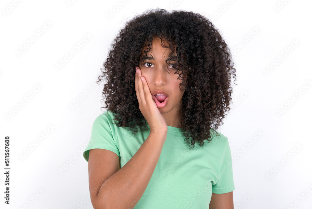 Shocked Young beautiful girl with afro hairstyle wearing green t-shirt over white wall looks with great surprisment being very stunned, astonished with unexpected news, Facial expressions concept. Shocked Young beautiful girl with afro hairstyle wearing green t-shirt over white wall looks with great surprisment being very stunned, astonished with unexpected news, Facial expressions concept.