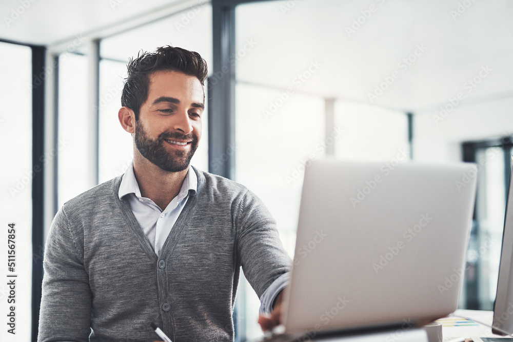 Working hard to maintain his lead in the business game. Shot of a young businessman working on a laptop in an office. Working hard to maintain his lead in the business game. Shot of a young businessman working on a laptop in an office.