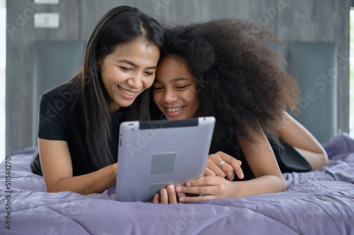 Asian-African American family Use a laptop to surf the Internet and  shop online. On the bed in bedroom in the holiday.