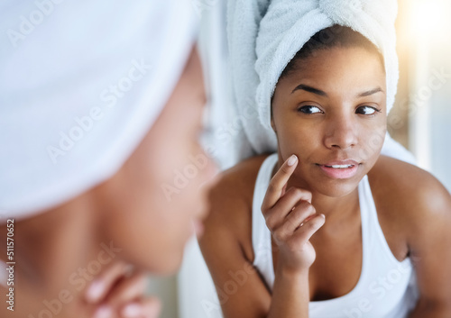 Her new skincare routine is showing results. Shot of a young woman inspecting her skin in front of the bathroom mirror.