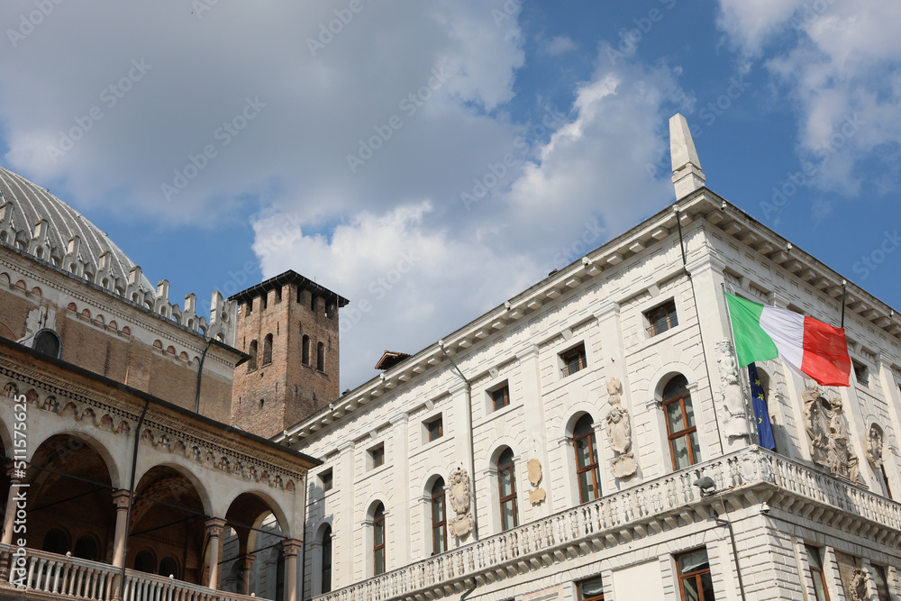 Padua, PD, Italy - May 15, 2022: Big Italian Flag and the ancient palaces such as PALAZZO DELLA RAGIONE and the medieval tower