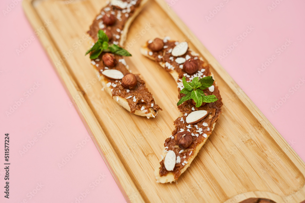 Bananas with peanut butter, almonds and nuts, on wood plate on wooden plate. Healthy food. Close up Bananas with peanut butter, almonds and nuts, on wood plate on wooden plate. Healthy food. Close up