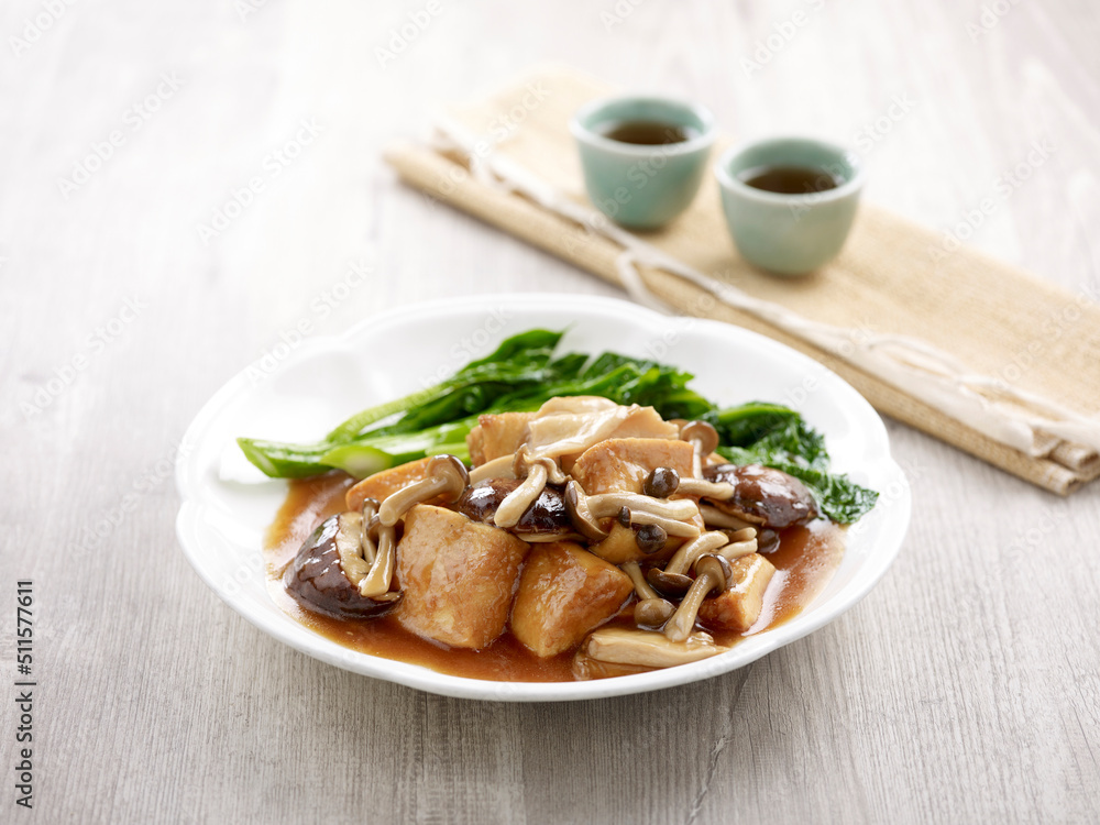 Braised Firm Tofu with Assorted Mushrooms with chopsticks served in a dish isolated on mat side view on grey background