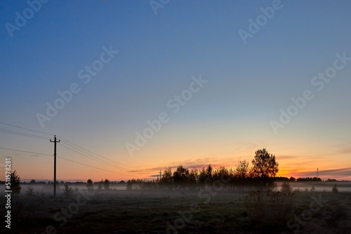 Field in the early foggy morning at sunrise. Amazing nature in early foggy morning on sunrise. Early morning landscape with the first rays of the sun.