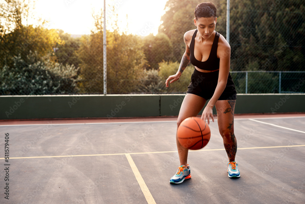 Warming up is essential. Full length shot of an attractive young sportswoman standing alone on a basketball court and warming up with the ball.