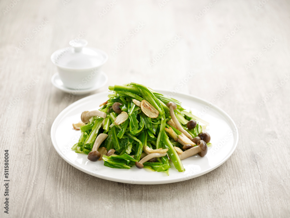 Stir-fried Chinese Chives and Wild Mushrooms with Garlic with chopsticks served in a dish isolated on mat side view on grey background Stir-fried Chinese Chives and Wild Mushrooms with Garlic with chopsticks served in a dish isolated on mat side view on grey background