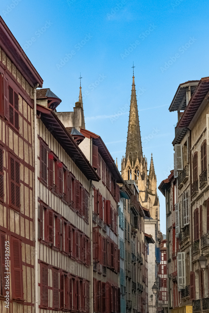 Bayonne in the pays Basque, typical facades with colorful shutters in the historic center, with the cathedral Sainte-Marie in background
