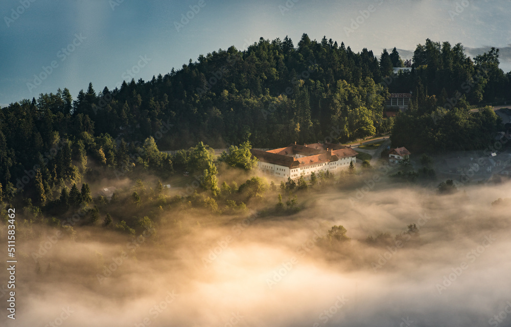 Fototapeta premium Lake Bled on a foggy spring morning with mist and fog in the valley. 