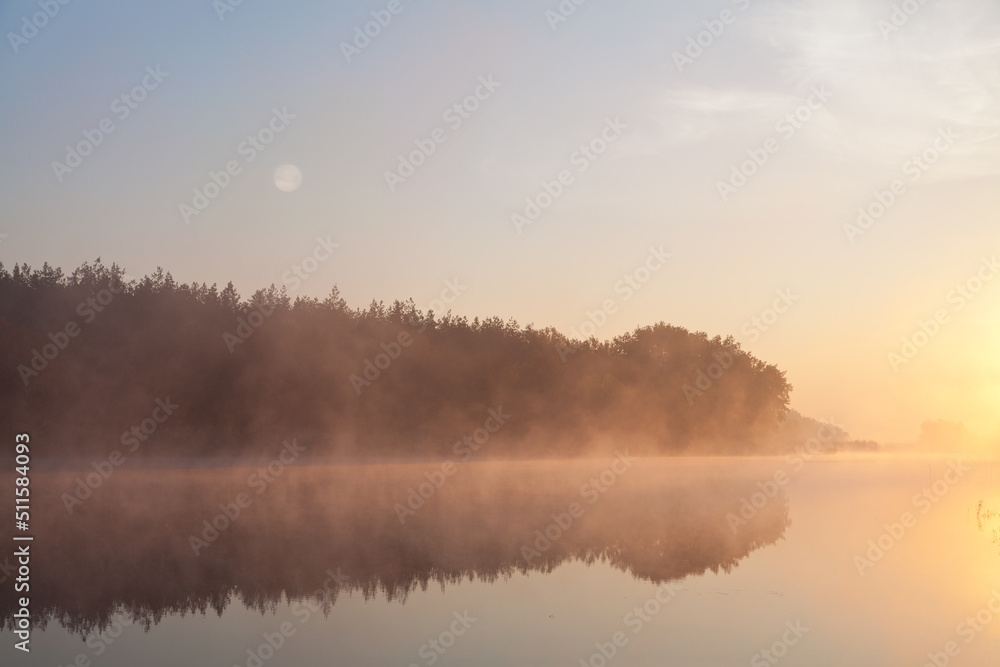 Foggy morning over calm river, pink fog against morning sun, full moon. Ukraine, peace.
