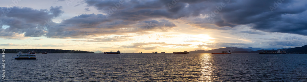 Big Container Ship parked in Burrard Inlet on the West Coast of Pacific Ocean. Colorful cloudy sunset sky. Vancouver, British Columbia, Canada. Panorama Nature Background Big Container Ship parked in Burrard Inlet on the West Coast of Pacific Ocean. Colorful cloudy sunset sky. Vancouver, British Columbia, Canada. Panorama Nature Background