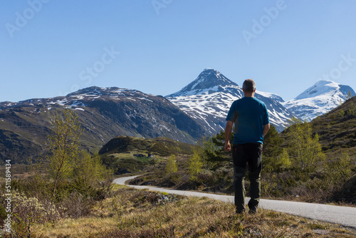 Back view of a man walking the winding road of the Ardal mountain pass in Norway