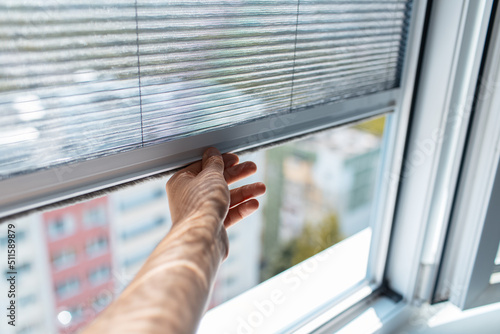 Close-up of male hand trying to open the modern mosquito net on plastic window.