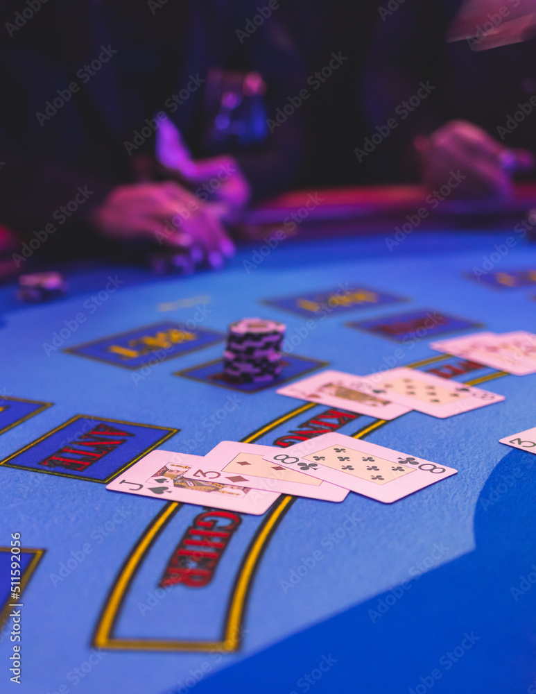Poker table view with a pack of cards, tokens, alcohol drinks, dollar money and group of gambling rich wealthy people playing poker in casino, with croupier Poker table view with a pack of cards, tokens, alcohol drinks, dollar money and group of gambling rich wealthy people playing poker in casino, with croupier