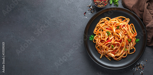 Linguini pasta with tomato sauce and parsley on a dark background. Top view, copy space.
