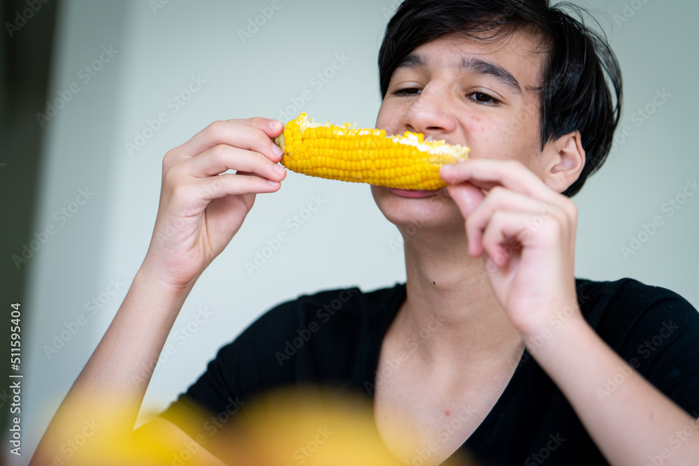 Summer snack, teenager sitting and eating corn High quality photo Summer snack, teenager sitting and eating corn High quality photo