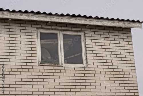 white brick attic of a private house with one window against a gray sky © butus