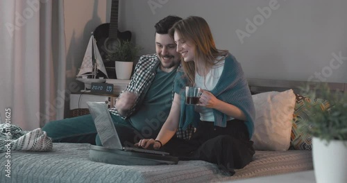 Husband going to his wife in their new house. Young couple watching a movie