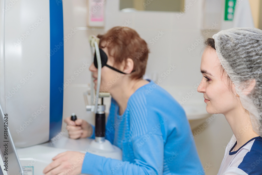 Fototapeta premium A girl optometrist examines the eyes of a patient using special modern equipment