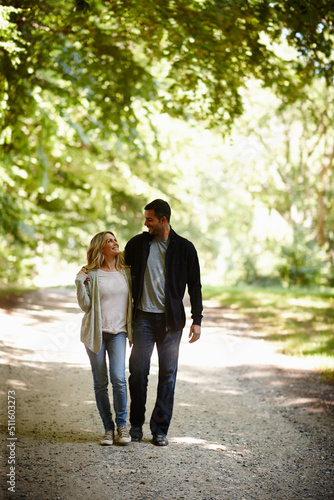 Always by each others side. Full length shot of a young couple walking arm in arm in a park.
