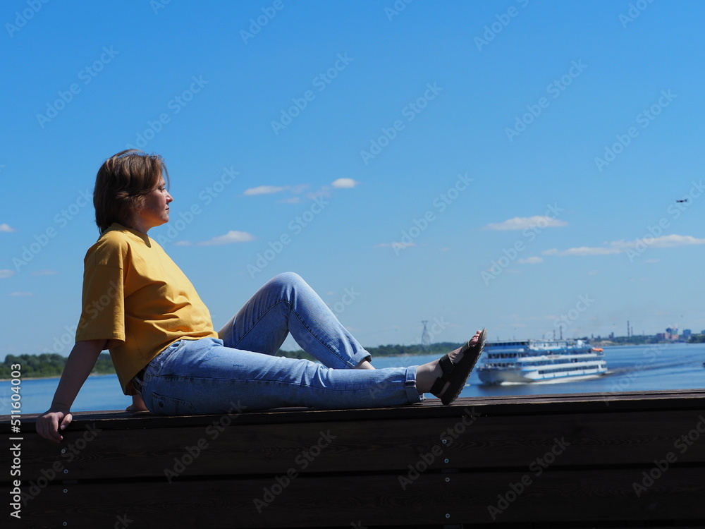 A girl is sitting on the pier, a cruise ship in the background. A girl is sitting on the pier, a cruise ship in the background.