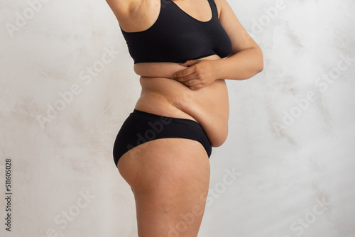 Принти на полотні Cropped overweight fat woman pinching and checking volume of sides in black bikini