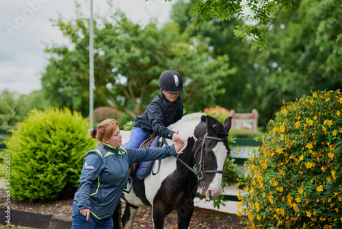 My trainer is helping me succeed. Shot of a horse riding trainer teaching a young girl how to ride a horse outdoors. © AS/peopleimages.com