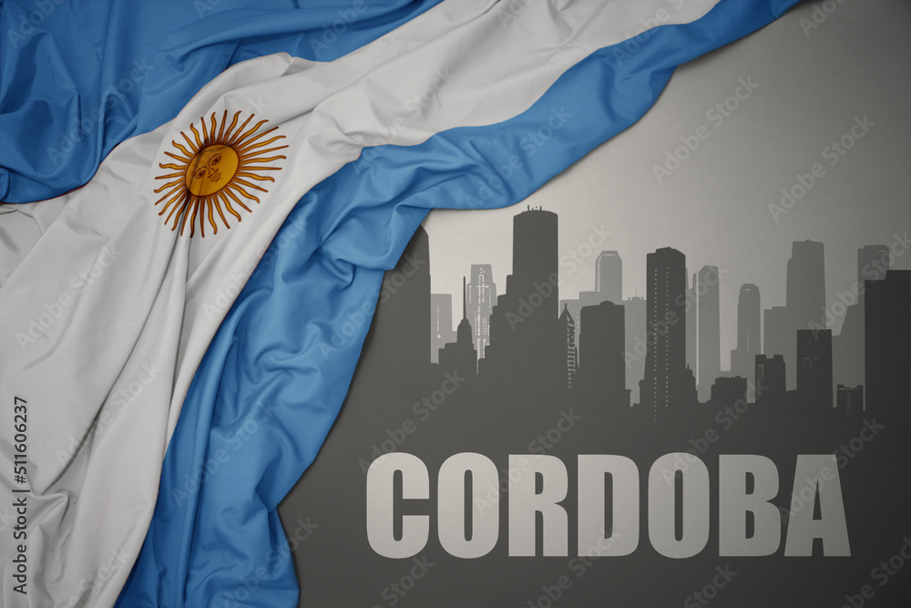 abstract silhouette of the city with text Cordoba near waving national flag of argentina on a gray background.