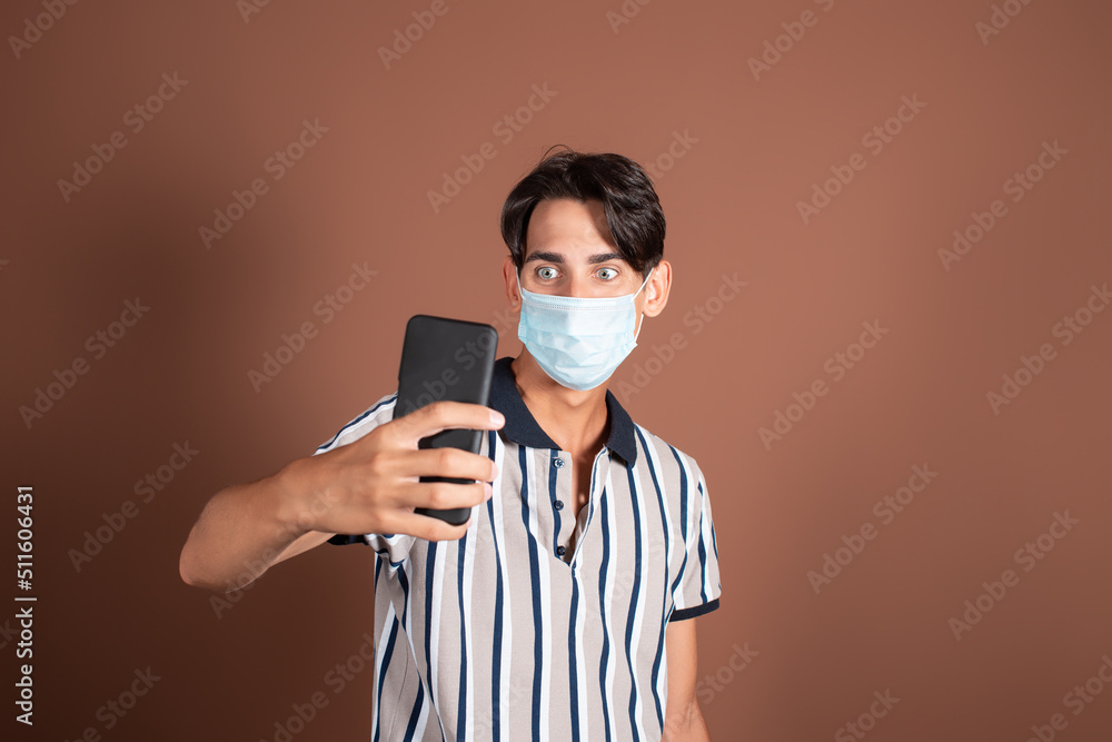Emotional young man in a medical mask on a brown background. Medicine and diseases by airborne droplets. Emotional young man in a medical mask on a brown background. Medicine and diseases by airborne droplets.