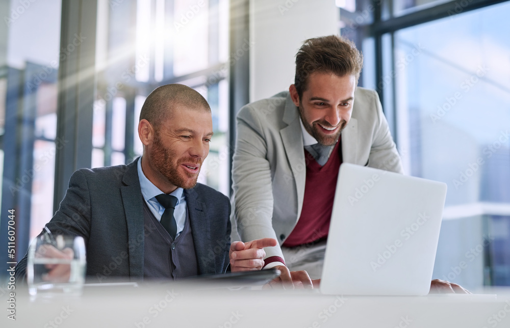 Getting together to get it done. Shot of two businessmen using a laptop together in a modern office. Getting together to get it done. Shot of two businessmen using a laptop together in a modern office.