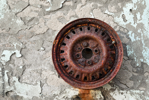 Detail of an old rusty car rims hanging from a scraped wall (textures, background, materials), Italy