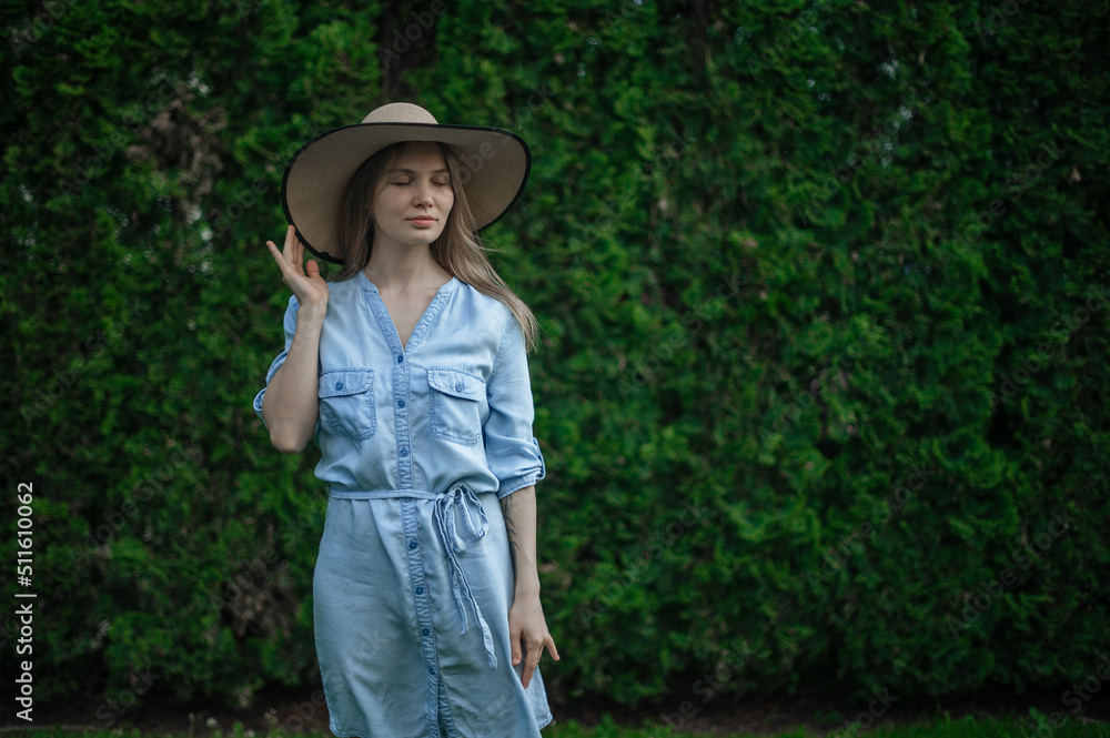 Romantic girl with hat outdoor in park. Green floral background