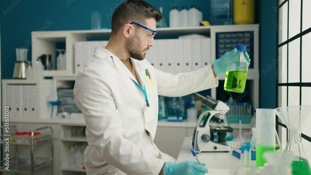 Young hispanic man wearing scientist uniform measuring liquid at laboratory Young hispanic man wearing scientist uniform measuring liquid at laboratory