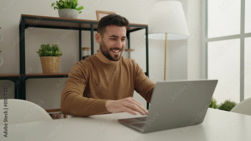 Young hispanic man using laptop sitting on table at home Young hispanic man using laptop sitting on table at home