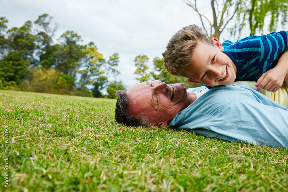 Sharing moments between father and son. Shot of a laughing father and son lying on grass. Sharing moments between father and son. Shot of a laughing father and son lying on grass.