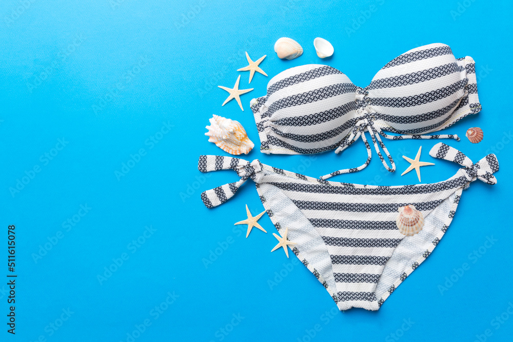 Naklejka premium Woman swimwear and beach accessories flat lay top view on colored background Summer travel concept. bikini swimsuit, straw hat and seasheels. Copy space Top view