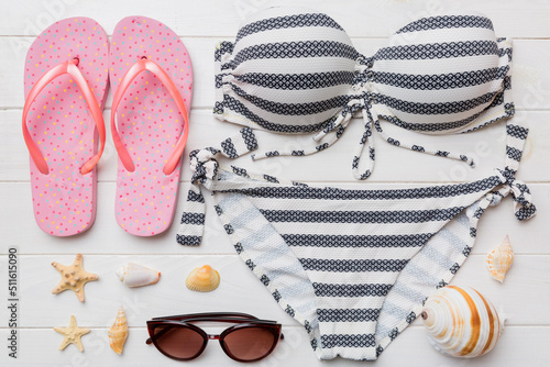 Woman swimwear and beach accessories flat lay top view on colored background Summer travel concept. bikini swimsuit, straw hat and seasheels. Copy space Top view