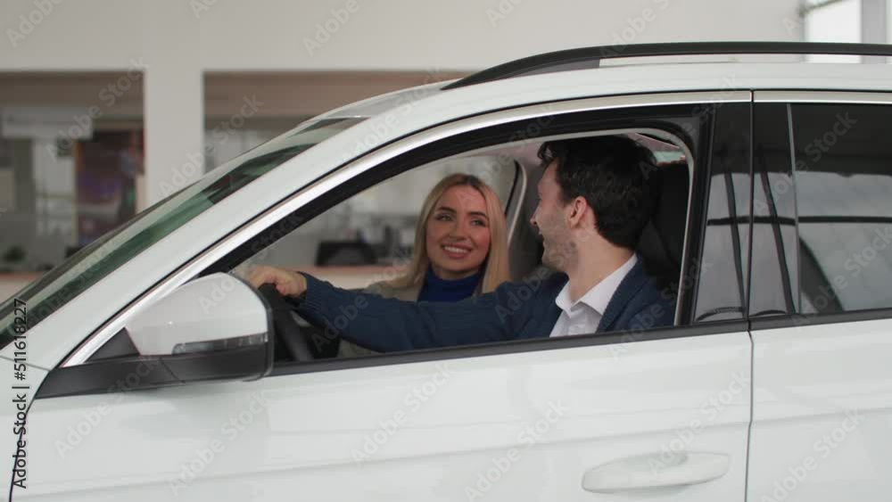 portrait of joyful man with his wife sitting at wheel of a car and showing keys to a new car from auto center, smiling and looking at camera portrait of joyful man with his wife sitting at wheel of a car and showing keys to a new car from auto center, smiling and looking at camera