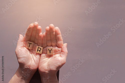 female hands hold wooden tiles with word Try on grey background