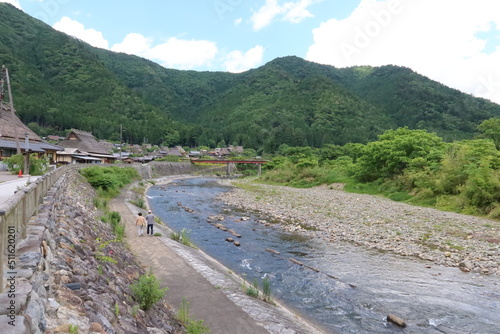 A scene of Japanese traditional houses with a thatched roof in the preserved area of them and Yura-gawa River in Miyama Town in Nantan City in Kyoto Prefecture in Japan 日本の京都f府南丹市美山町にある茅葺の家々保存地区の風景 photo